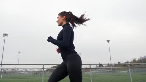 Sporty-Woman-in-Black-Sportswear-Running-on-the-Track,-Exterior-Slomo