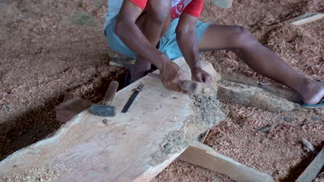 Poor-carpenter-sculpting-timber-piece-with-chisel-and-hammer-sits-on-shavings