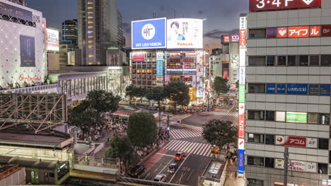 Jr-Zug-Am-Bahnhof-Shibuya-Mit-Blick-Auf-Die-Shibuya-Kreuzung-Bei-Nacht-Mit-Verkehr-Und-Fußgängern-In-Tokio,-Japan