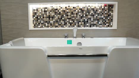 Große-Moderne-Weiße-Badewanne-Mit-Designerfliesen-Im-Wandhintergrund