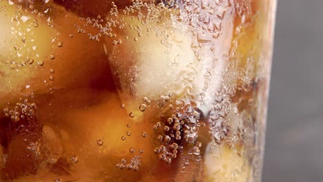 Glass-of-fizzy-coca-cola-with-bubbles-and-ice-cubes---close-up-shot-4k