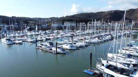 Luxury-yachts-and-sailboats-moored-in-Conwy-marina-mountain-waterfront-aerial-view-North-Wales-orbit-right