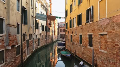 Narrow-canal-of-Jewish-ghetto-neighborhood-of-Cannaregio-in-Venice-with-hanging-clothes-and-moored-boats,-Italy