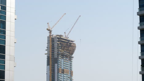 Dubai-skyscraper-under-construction,-cranes-on-tall-apartment-building
