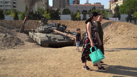 Azerbaijani-family-look-at-captured-Armenian-tank-in-Trophy-park,-Baku,-Azerbaijan