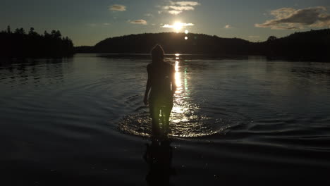 Wide-sunset-shot-of-a-woman-walking-out-of-the-water-after-a-swim-in-Black-Lake