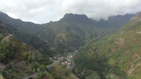 Winding-Mountain-Pass-Overlooking-Small-Town-On-Foothills-Of-Green-Mountain-In-Madeira-Island,-Portugal