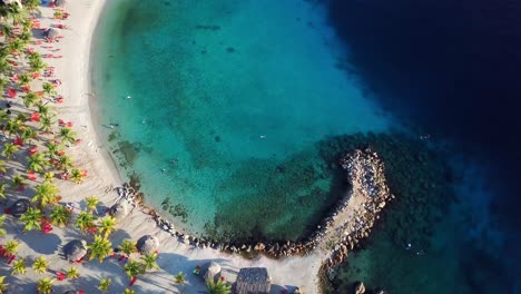 Overhead-aerial-view-of-Blue-Bay-beach-in-Curacao,-Dutch-Caribbean-island,-palm-trees-on-a-sunny-day