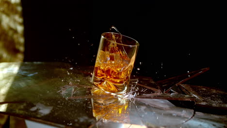 A-glass-of-whiskey-breaks-a-glass-surface-in-super-slow-motion,-symbolic-of-alcoholism-and-the-negative-effects-of-drinking