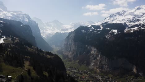 Aerial-is-flying-high-up-from-Wengen-and-shows-Lauterbrunnen-Town-from-a-distance,-Switzerland
