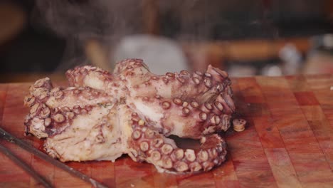 Cinematic-food-videography-tracking-shot-of-freshly-cooked-octopus-placed-on-a-chopping-board-with-steaming-hot-water-vapor-slowly-vaporizing-from-the-surface
