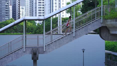 Man-wearing-singlet-walking-up-covered-staircase,-overhead-pedestrian-bridge-in-Toa-Payoh-,-Singapore