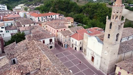 Aerial-shot-of-a-bell-tower-in-a-square-of-a-small-Italian-town