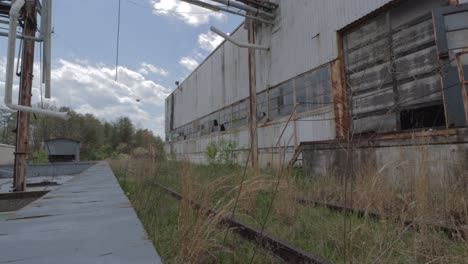 Slider-Footage-of-Overgrown-Railroad-Tracks-at-an-Abandoned,-Decaying-Factory