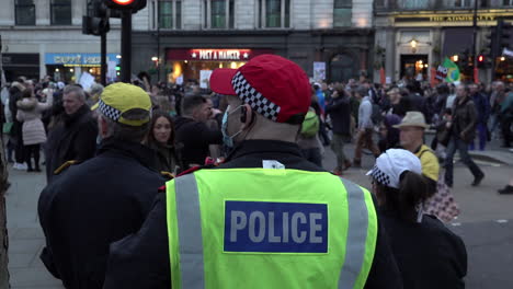 Three-senior-officers-of-the-Metropolitan-Police-Force-wearing-protective-face-masks-stand-and-watch-as-large-protest-passes-by