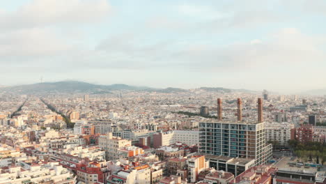 Rising-establishing-drone-shot-over-dense-Barcelona-city-at-sunrise