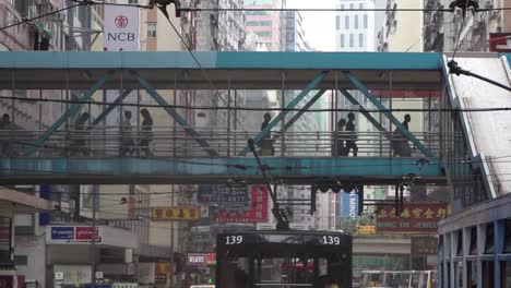 Pedestrian-walking-in-metal-suspension-bridge-crossing-a-traffic-narrow-road