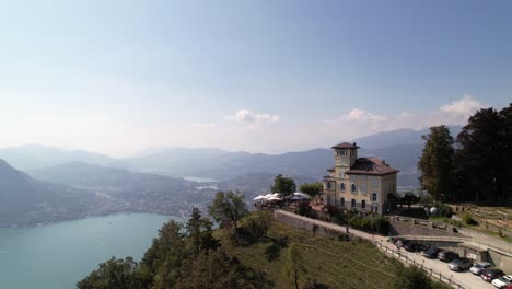 Errichten-Sie-Die-Stadt-Lugano-Hinter-Dem-Restaurant-Monte-Bre,-Episches-Stadtpanorama,-Luftaufnahme
