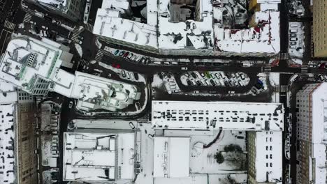 Aerial-view-over-wet-streets-and-snowy-rooftops-in-Warsaw,-cloudy,-winter-day-in-Poland---top-down,-drone-shot