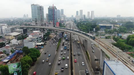 Forward-aerial-of-car-and-MRT-train-traffic-in-Jakarta,-Indonesia