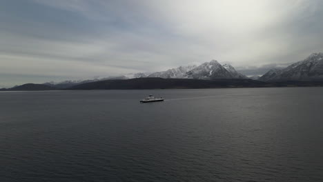 Cinematic-flight-of-ferry-boat-towards-Breivikeidet,-snowy-Lyngen-Alps-in-background