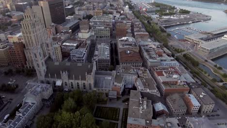 Looking-up-on-a-city-near-a-river-during-sunset-aerial,-Montreal