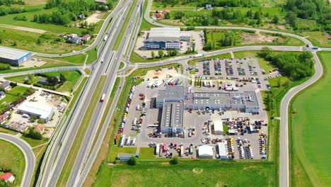 Buildings-of-logistics-center,-warehouses-near-the-highway,-view-from-height,-a-large-number-of-trucks-in-the-parking-lot-near-warehouse