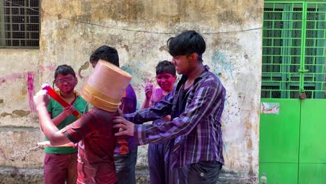 Kolkata-,-West-Bengal-,-India---03-31-2022:-Group-of-Cheerful-kids-with-color-bucket,-pichkari-shouting-at-camera-after-playing-with-colorful-Holi-powder-during-festival-celebration