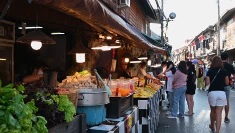 Vendedores-Preparando-Comida-Para-Dar-A-Los-Turistas-Mientras-La-Gente-Camina-Por-La-Calle,-Calle-Peatonal,-Chiang-Khan,-Loei-En-Tailandia