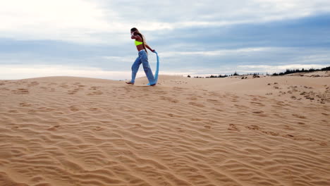 Red-sand-dunes-scenic-landscape,-young-actress-walking-on-natural-environment-with-fashioned-modern-clothing