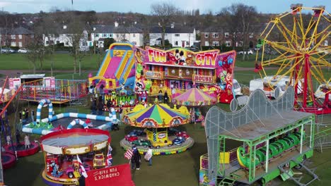 Small-town-fairground-Easter-holidays-funfair-rides-in-public-park-aerial-view-slow-left-orbit