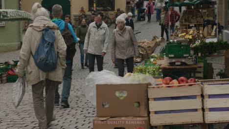 Elderly-people-walking-past-fruit-assortments-in-Balvarian-downtown-produce-market-at-noon-in-Tubingen,-Germany,-Europe,-panning-shot