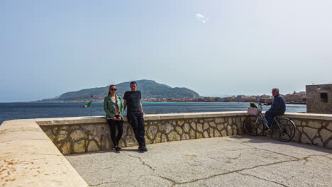 Trapani,-Sicily,-Italy:-View-of-a-couple-busy-taking-photos-along-with-the-locals-while-on-the-beach-of-Trapani-old-town-while-facing-the-sea