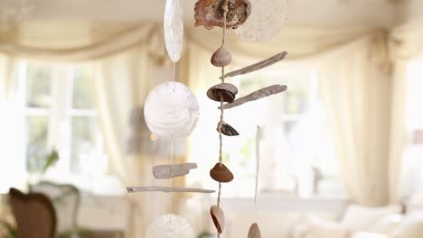 Wind-chime-made-from-sea-shells-inside-a-brightly-lit-interior-living-room-on-a-sunny-morning