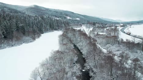 Aerial-Drone-View-Of-Snowscape-Countryside-With-Mountain-River-And-Road-During-Winter