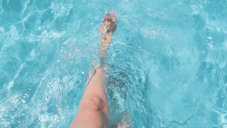 Frau-Sitzt-Am-Pool,-Spritzt-Wasser-Mit-Beinen,-Klares-Kristallklares-Wasser-In-Zeitlupe