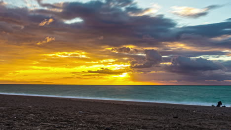 Static-view-of-sunset-over-golden-sky-over-the-sea-in-timelapse-over-sandy-beach