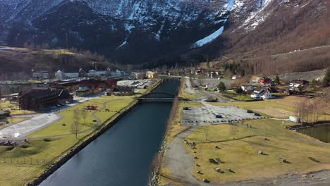 Flam-Norway---Aerial-flying-in-from-seaside-above-river-and-towards-town-center-during-morning-sunrise