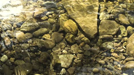 A-crystal-clear-pool-of-water-shows-rocks-and-pebbles-on-a-warm-summers-day
