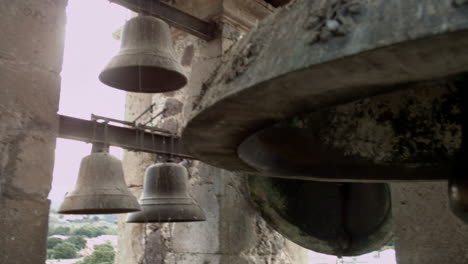Church-bells-mounted-in-high-tower-in-the-public-square-of-a-small-mexican-town,-that-can-be-heard-by-the-surrounding-community