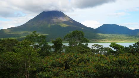 Gesamtaufnahme,-über-Den-Bäumen,-Malerischer-Blick-Auf-Den-Arenalsee-Und-Den-Vulkan-In-Costa-Rica,-Helles,-Sonniges-Licht-Im-Hintergrund