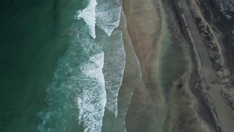 Flying-over-the-ocean-looking-down-at-the-waves-and-the-beach