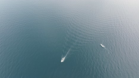 Two-boats-on-a-blue-lake-turning-around-each-other-on-the-quiet-water-surface