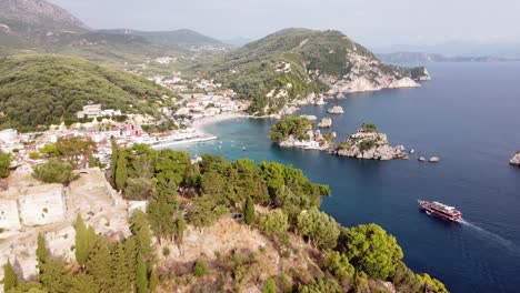 Cruise-Boat-Sails-to-Scenic-Coastal-Village-Parga-in-Epirus,-Greece---Aerial