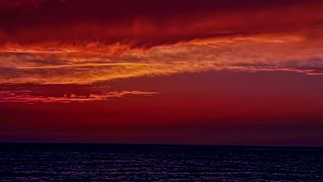 Beautiful-cloudscape-over-the-sea-with-sun-setting-in-timelapse-in-the-red-evening-sky