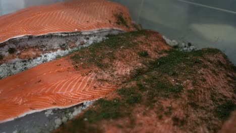 Three-orange-trout-fillets-laying-in-box-beeing-sprinkled-with-green-dill-falling-from-above---Handheld-slow-motion