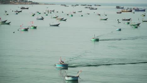 Fishermen-sail-on-coracles-between-moored-fishing-boats-in-Vietnam-quiet-port
