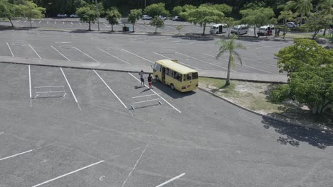 Aerial-view-of-tourists-get-out-from-bus-on-parking-Dunn's-River-Falls,-Jamaica