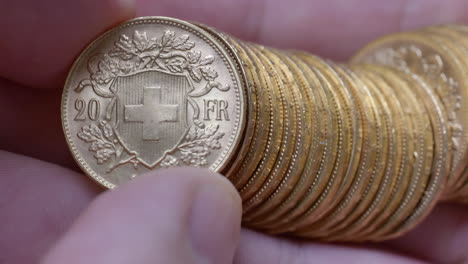 Macro-shot-of-person-checking-several-rare-golden-vreneli-francs-in-hand