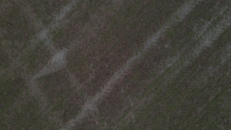 A-drone-shot-taking-off-from-and-ascending-over-a-wet-and-muddy-farm-field